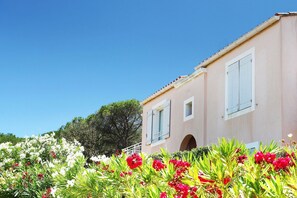 Un bâtiment à la façade de couleur claire, avec des volets blancs et une entrée en arc de cercle bien visible.
