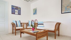 A room with a wooden coffee table, two sofas with striped cushions, and a potted plant. - Spacious Apt Near the Beach (Saint-Aygulf)