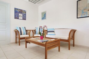 Um quarto com uma mesa de centro de madeira, dois sofás com almofadas listradas e um vaso de plantas.
