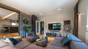 A modern living room with a stone accent wall, a flat-screen TV, and a comfortable seating area.
