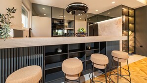 A modern kitchen with a central island, bar stools, and a hanging light fixture.