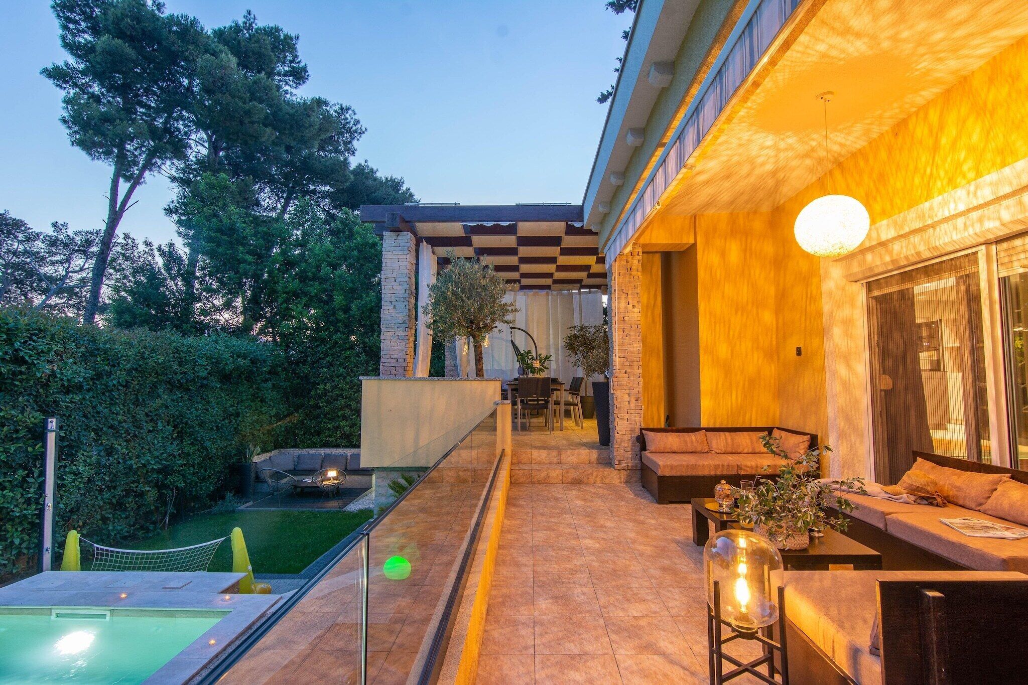 Ein moderner Außenbereich mit Pool, Sitzgelegenheiten und einer Pergola mit Schachbrettmuster.