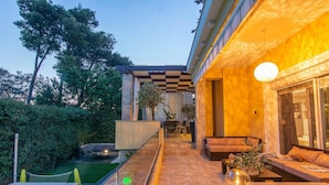 A modern outdoor living area with a pool, seating, and a checkered pergola.