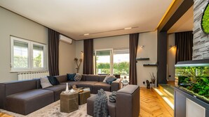 A modern living room with a sectional sofa, a coffee table, and a large window with curtains.