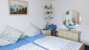Une chambre à coucher avec un lit, une commode, des étagères et un tableau.