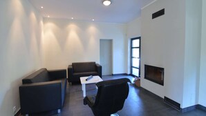 Un salon moderne avec des canapés sombres, une table basse blanche et une cheminée.