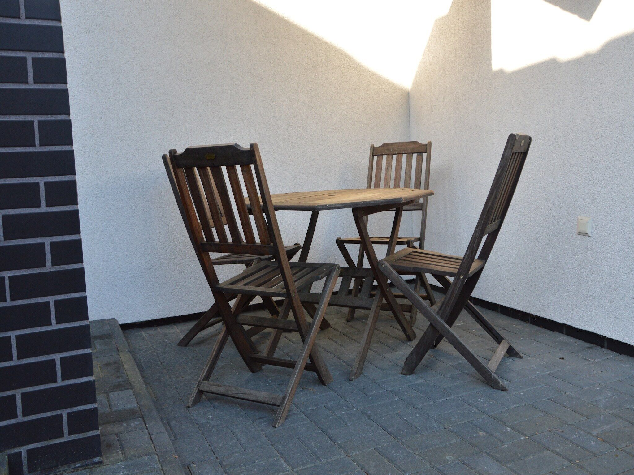 A patio area with a wooden table and four chairs.