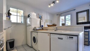 Ett kompakt kök med tvättmaskin, mikrovågsugn och diskho.