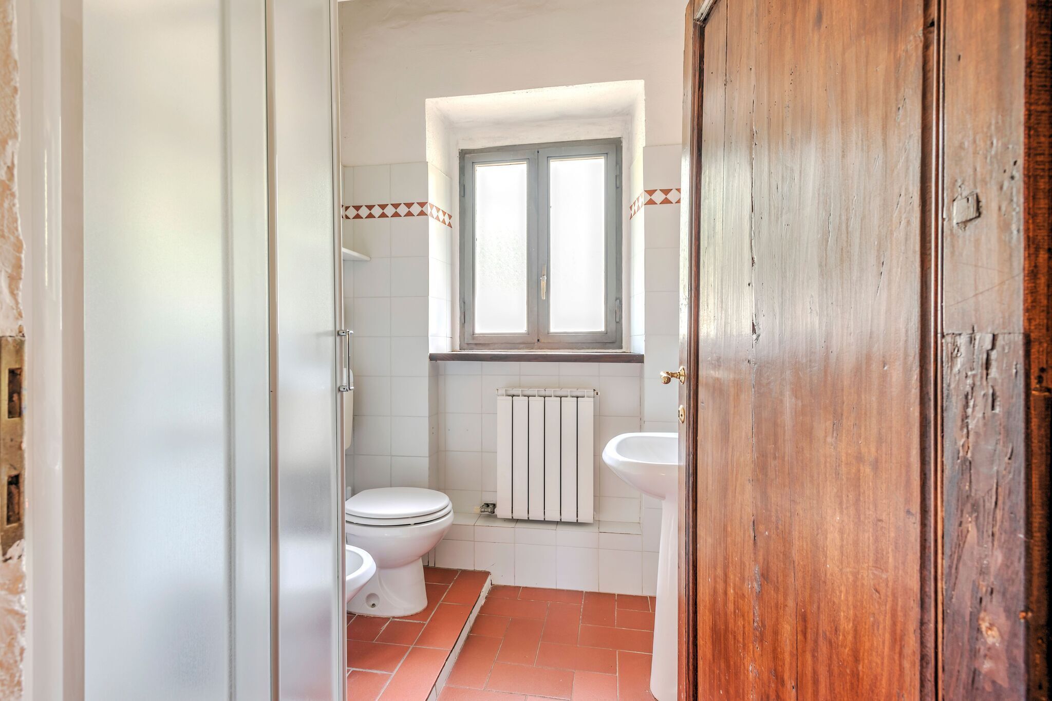 Ein kleines Badezimmer mit Toilette, Waschbecken und einem Fenster über dem Waschbecken.