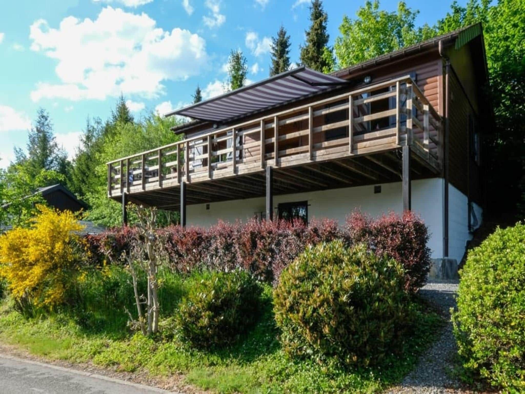A two-story building with a balcony, surrounded by greenery and trees.