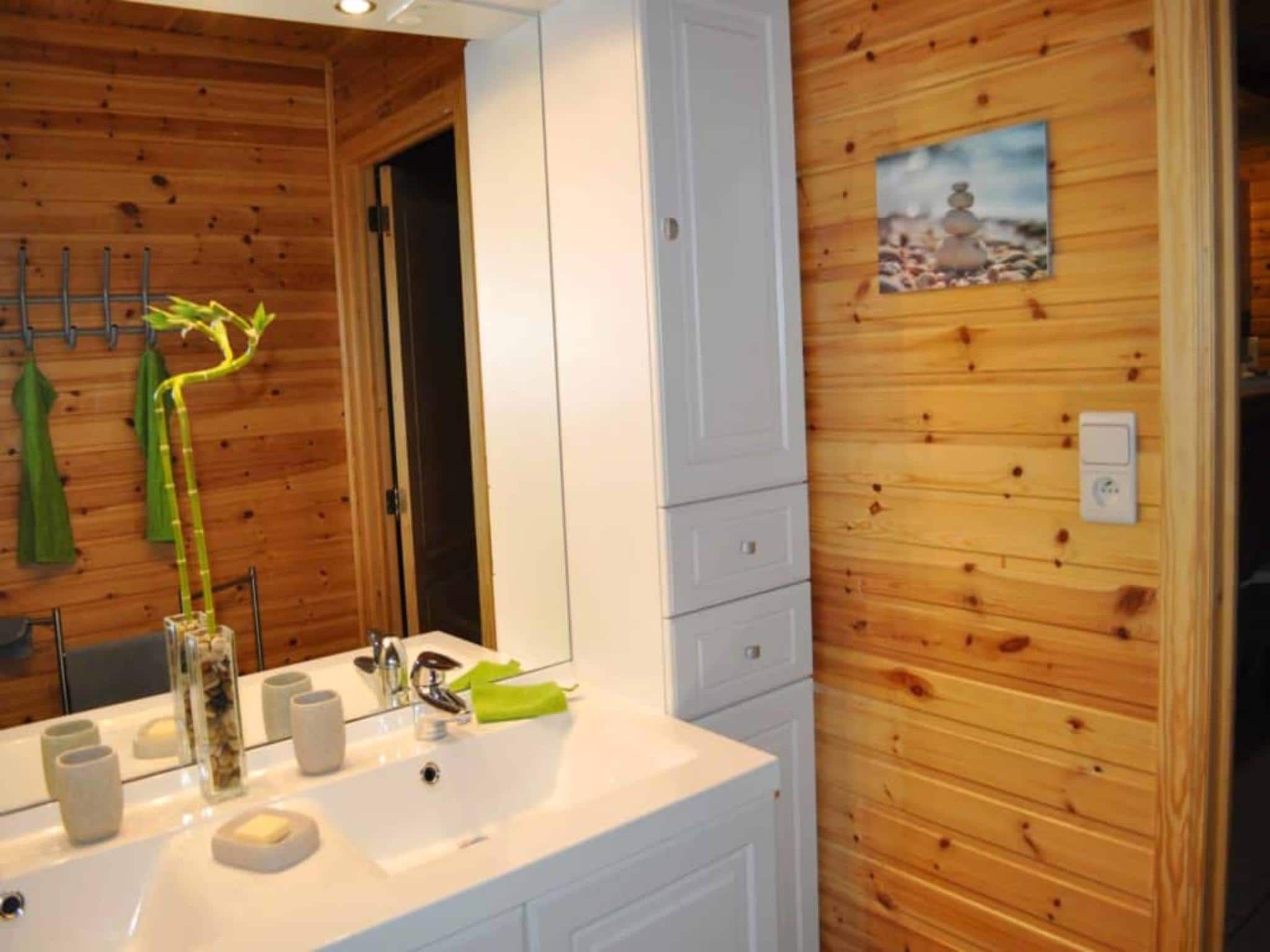 A bathroom with wooden panel walls, a white sink, and a mirror.