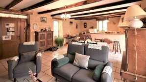 A cozy living room with a sofa, armchairs, and a dining area with a table and chairs.