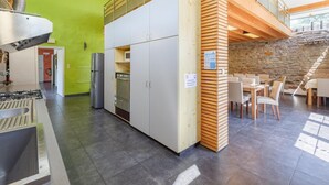 Een moderne keuken met inbouwapparatuur, een eethoek met tafels en stoelen, en een stenen muur.