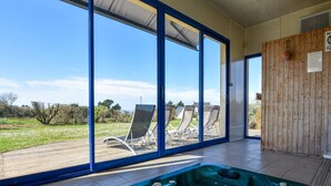 Un espace bien-être comprenant un jacuzzi, de grandes portes-fenêtres coulissantes et un coin salon extérieur.