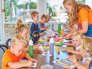 A group of children engaged in a craft activity at a table with various art supplies.