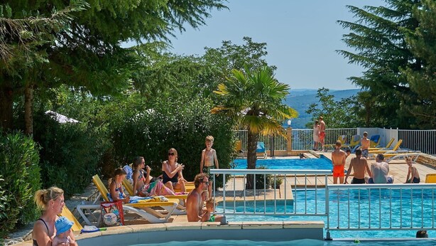 A pool area with multiple pools, lounge chairs, and people swimming and relaxing. - Villa in France with Private Garden (Lanzac)