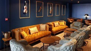 A cozy lounge area with a sofa, armchairs, and a coffee table. There are framed musical instruments on the wall. - Villa in France with Private Garden (Lanzac)