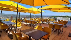 An outdoor dining area with yellow umbrellas and chairs, tables, and a view of the hills. - Villa in France with Private Garden (Lanzac)