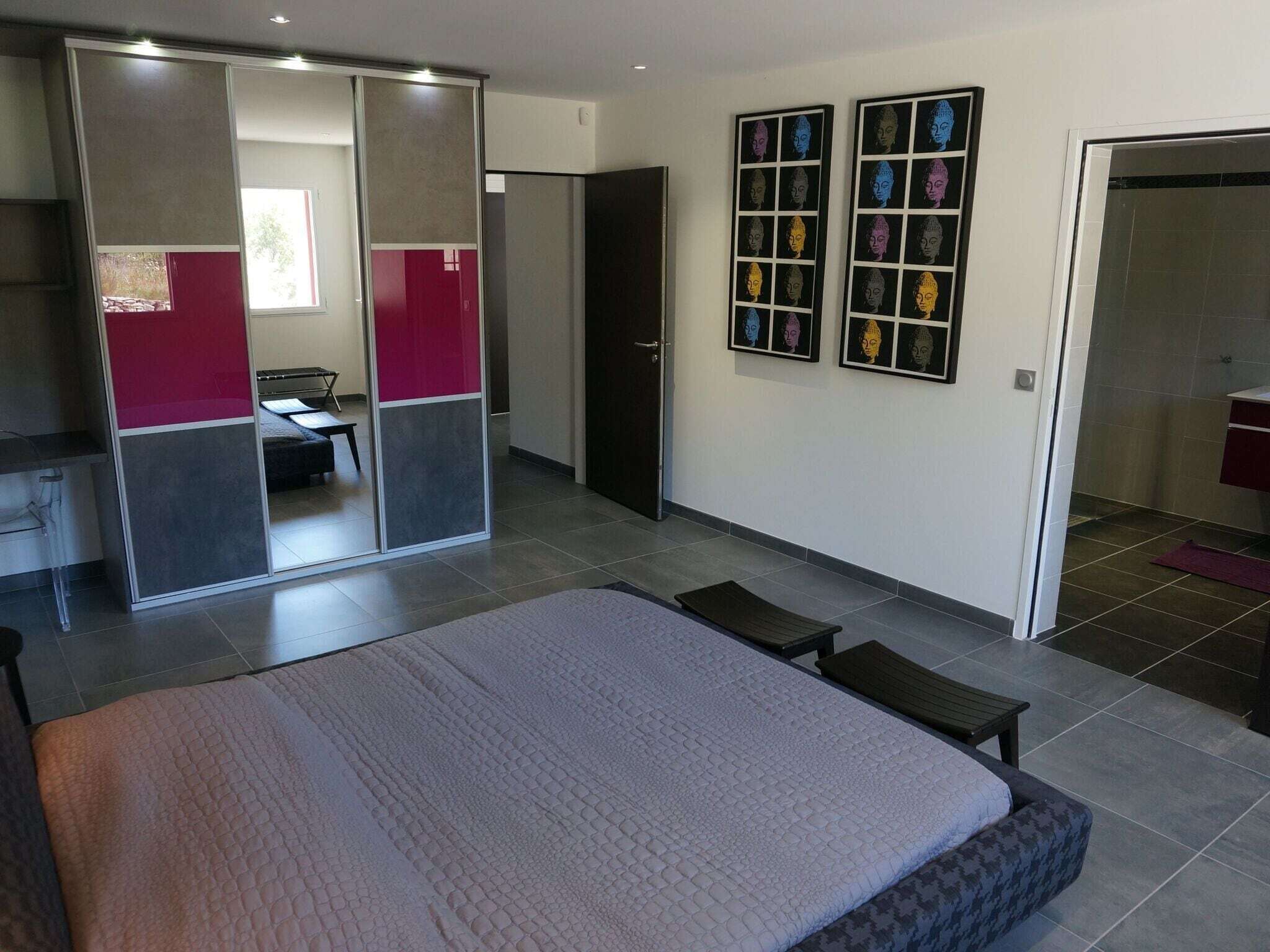 Un dormitorio moderno con cama, escritorio y armario. Hay dos cuadros enmarcados en la pared.