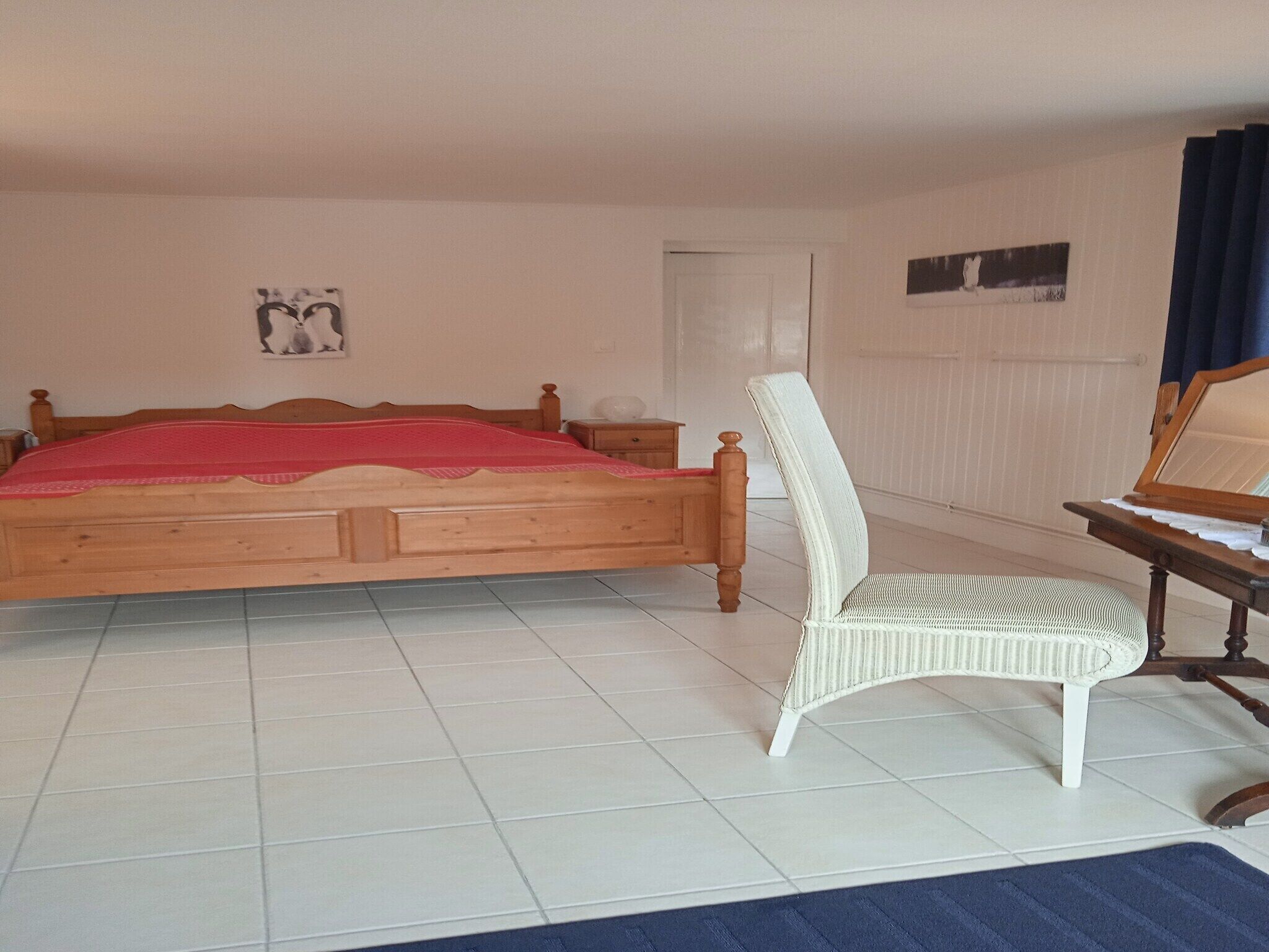 Une chambre à coucher avec un lit en bois, une chaise blanche et une petite table.