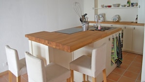 A compact kitchen with a wooden countertop, a sink, and a small dining area with chairs.