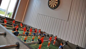 Un tavolo da calcio con figurine miniature e una dartboard appesa al muro.