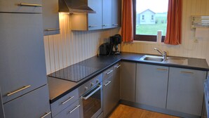 Una cucina compatta con forno integrato, una macchina per il caffè e una finestra con tende.