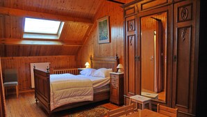 Una stanza in legno con un letto, una scrivania, una sedia, un armadio e un lucernario.