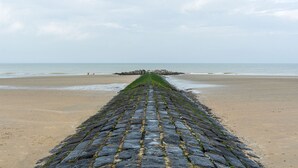 A cobblestone pathway leading to a rocky outcrop on a beach. - Nice holiday home in Westende-Bad with sauna and pingpong (Westende)