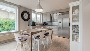 A modern kitchen with a dining area, wooden flooring, and a large window overlooking greenery. - Nice holiday home in Westende-Bad with sauna and pingpong (Westende)