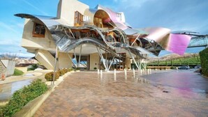 Un bâtiment moderne à l’architecture originale, doté d’une façade incurvée et métallique, et d’une entrée imposante.