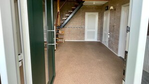 A hallway with a carpeted floor, a staircase with wooden railings, and a door at the end.