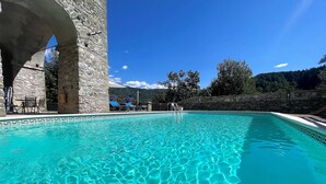 A clear blue pool with stone walls and a stone archway.
