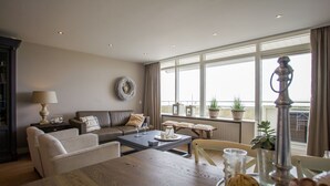 A modern living room with a sofa, coffee table, and a view of the city through large windows.