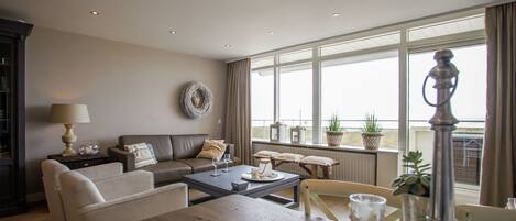 A modern living room with a sofa, coffee table, and a view of the city through large windows.