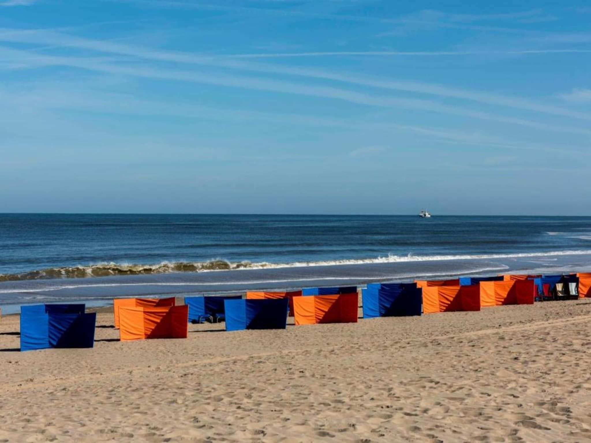 Une plage avec des tentes et un bateau au loin.