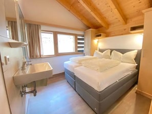 A bedroom with a bed, a sink, and a window.