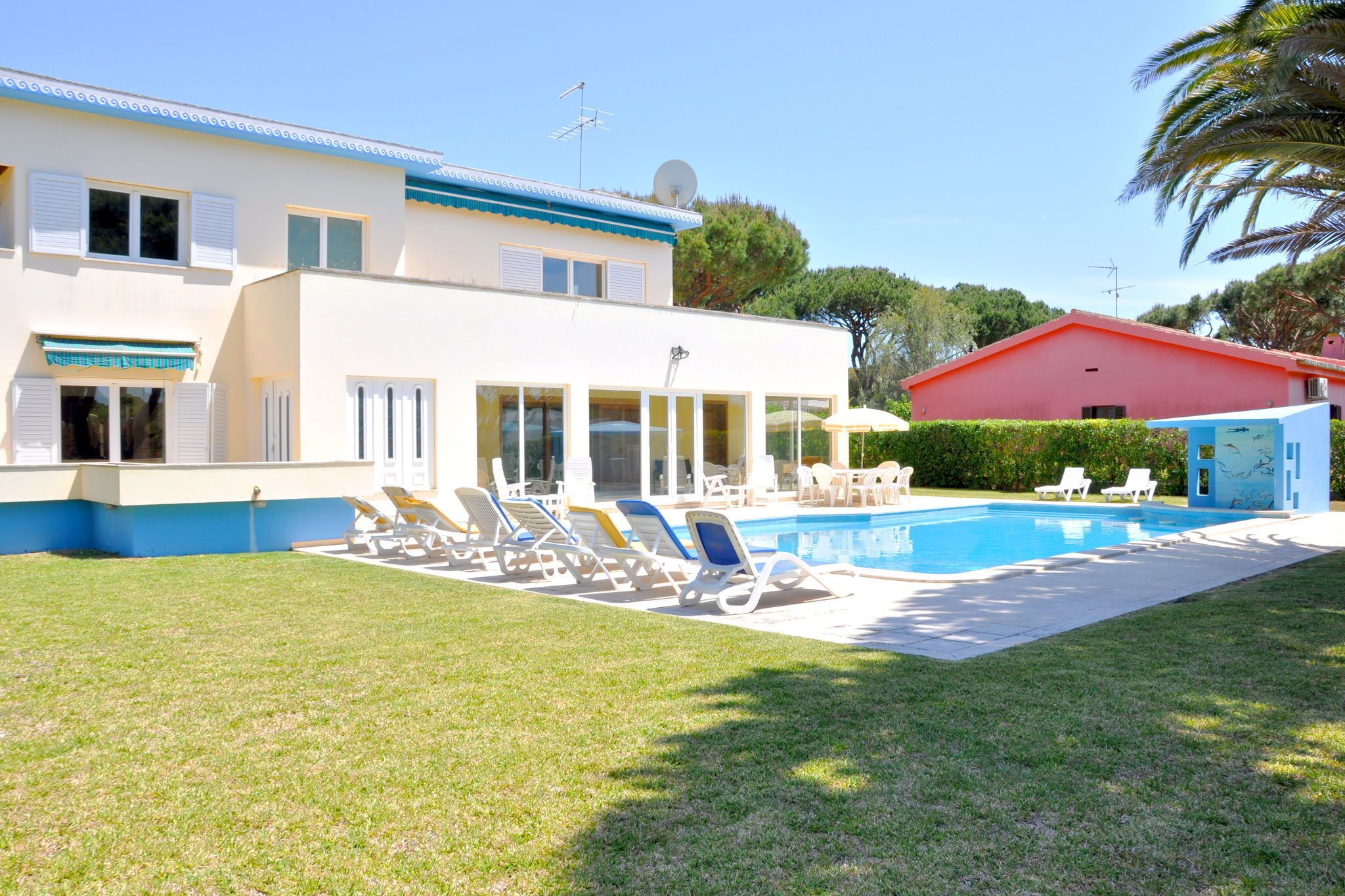 A pool area with lounge chairs and a building with a blue roof.