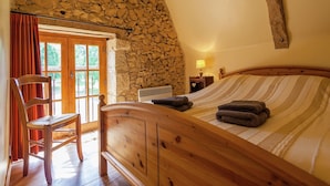 Een slaapkamer met een stenen muur, een houten bed en een stoel.