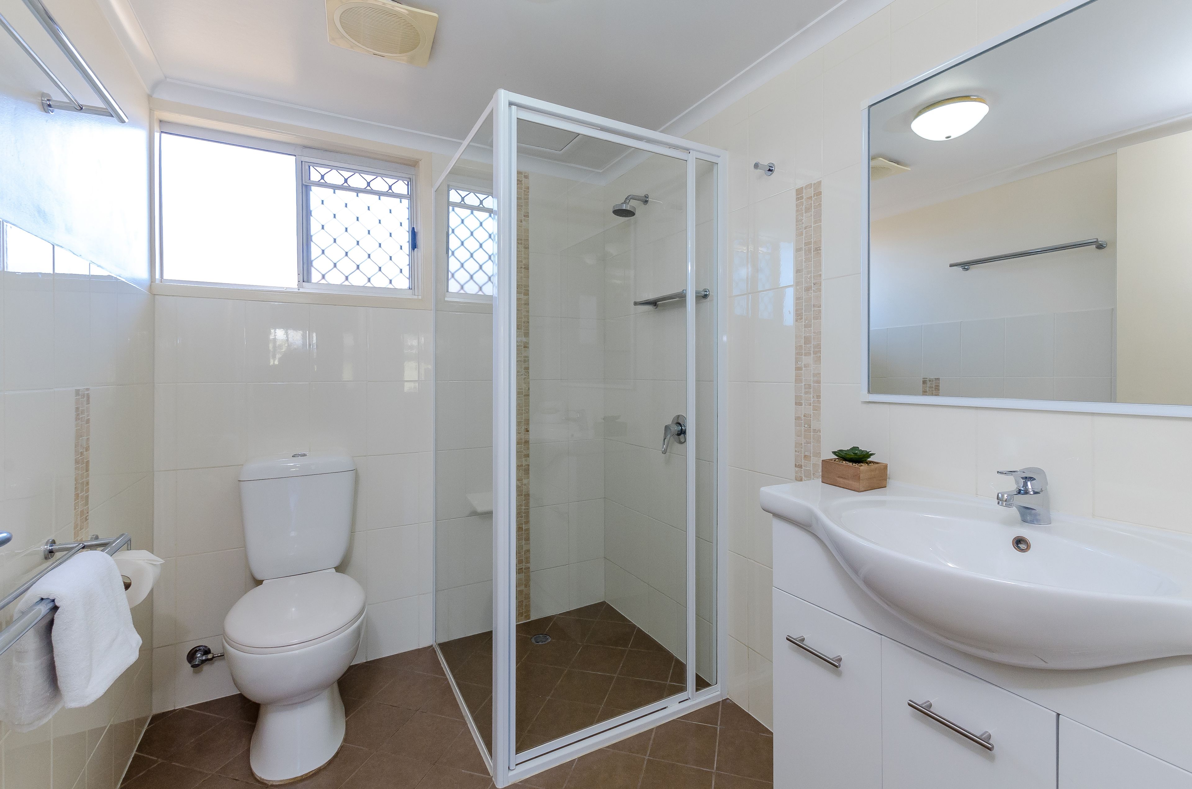 Un bagno con il water, una cabina doccia in vetro, un lavandino e uno specchio.