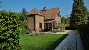 Une maison en briques dotée d’un patio, d’un espace salon extérieur et d’une pelouse bien entretenue.
