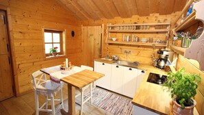 A wooden cabin with a kitchen area including a table, chairs, a sink, and a stove. - Chalet in Rauris near Ski Paradise (Rauris)