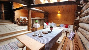 A rustic wooden cabin interior with a dining table set for four, a sofa with cushions, and a wooden bench. - Chalet in Rauris near Ski Paradise (Rauris)