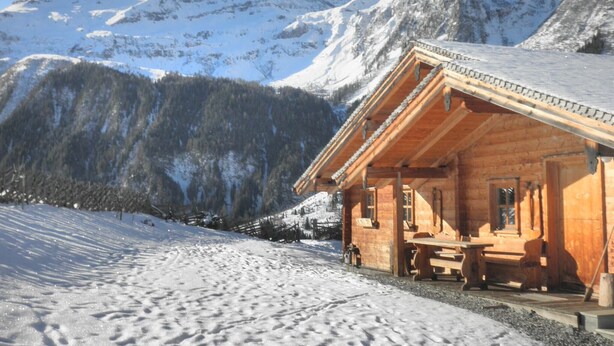 A wooden cabin with a porch, set against a snowy mountain backdrop. - Chalet in Rauris near Ski Paradise (Rauris)
