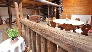 A rustic wooden interior with a round wooden table and heart-shaped chairs, a wooden cabinet, and a potted plant. - Chalet in Rauris near Ski Paradise (Rauris)