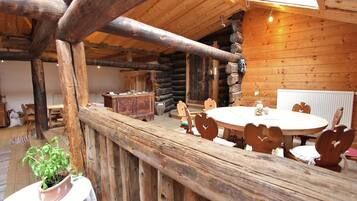 Ein rustikaler Holzinnenraum mit einem runden Holztisch, herzförmigen Stühlen, einem Holzschrank und einem Blumentopf.