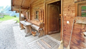 A wooden cabin with a porch, a bench, a table, and a door. - Chalet in Rauris near Ski Paradise (Rauris)