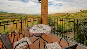 A balcony with a table and chairs, overlooking a scenic landscape.