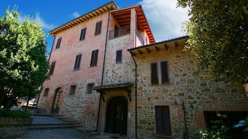 Ein traditionelles Steinhaus mit einem oberen Teil aus Backsteinen, einem Steineingang und einem Kopfsteinpflasterhof.