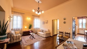 A cozy living room with a sofa, a coffee table, and a dining area with chairs.